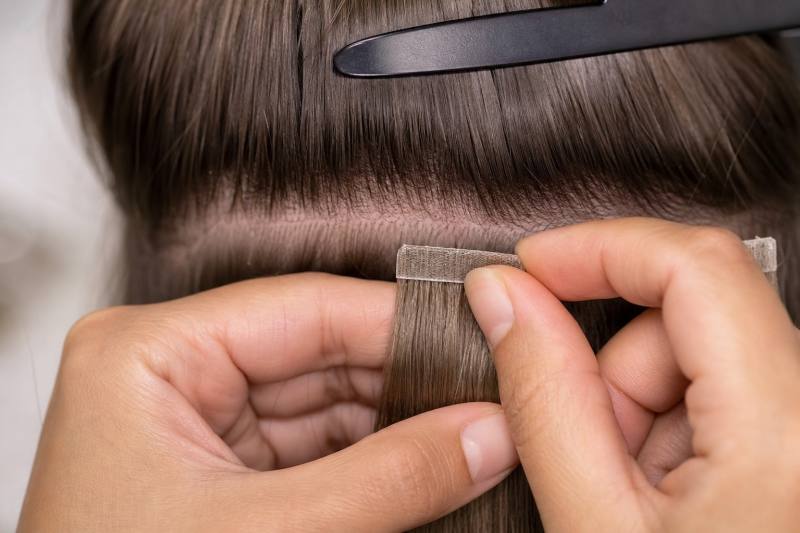 Client admiring their new, voluminous hair after a successful custom hair extension process, showcasing seamless blend and natural movement.